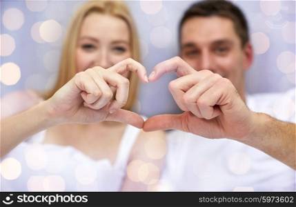 love, valentines day, relationships and people concept - close up of happy couple showing heart shape hand sigh in bed over lights background