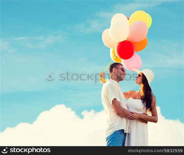love, wedding, summer, dating and people concept - smiling couple wearing sunglasses with balloons hugging over blue sky and cloud background
