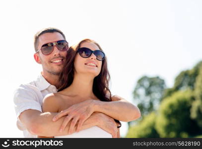 love, wedding, summer, dating and people concept - smiling couple wearing sunglasses hugging in park