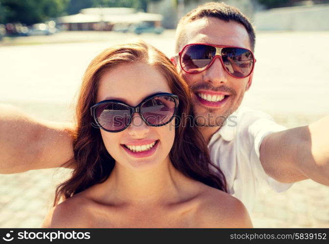 love, wedding, summer, dating and people concept - smiling couple wearing sunglasses making selfie in city