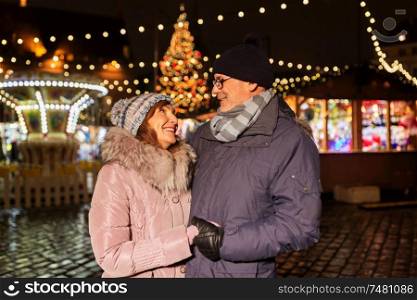 love, winter holidays and people concept - happy senior couple at christmas market on town hall square in tallinn, estonia. happy senior couple at christmas market
