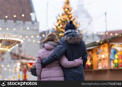 love, winter holidays and people concept - happy senior couple hugging at christmas market on town hall square in tallinn, estonia. happy senior couple hugging at christmas market