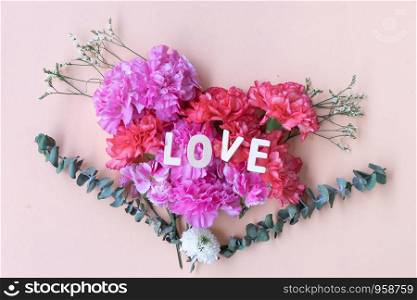 love wooden word on fresh carnation flowers bouquet