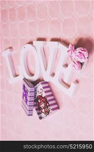 Love word and gift boxes against pink background