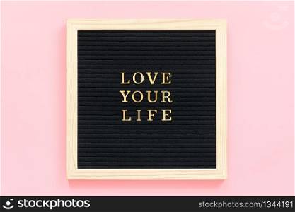 Love your life. Motivational quote in gold letters on black letter board on pink background, central composition . Top view Flat lay Copy space Concept inspirational quote of the day.. Love your life. Motivational quote in gold letters on black letter board on pink background, central composition . Top view Flat lay Copy space Concept inspirational quote of the day