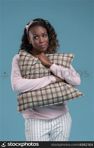 Lovely african woman holding and embracing pillow on blue background