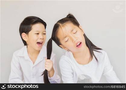 Lovely Asian couple school kids playing together, 7 and 10 years old, over gray background