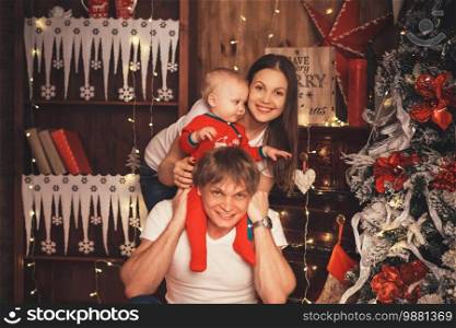 Lovely Baby boy in Santa Claus costume for Christmas. Mother, father and little son playing. Happy family