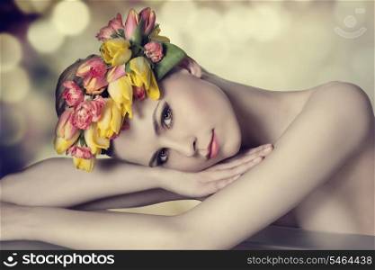 lovely beauty girl with spring floral wreath, colorful make-up, fresh skin and naked shoulders lying on a table and looking in camera with calm expression