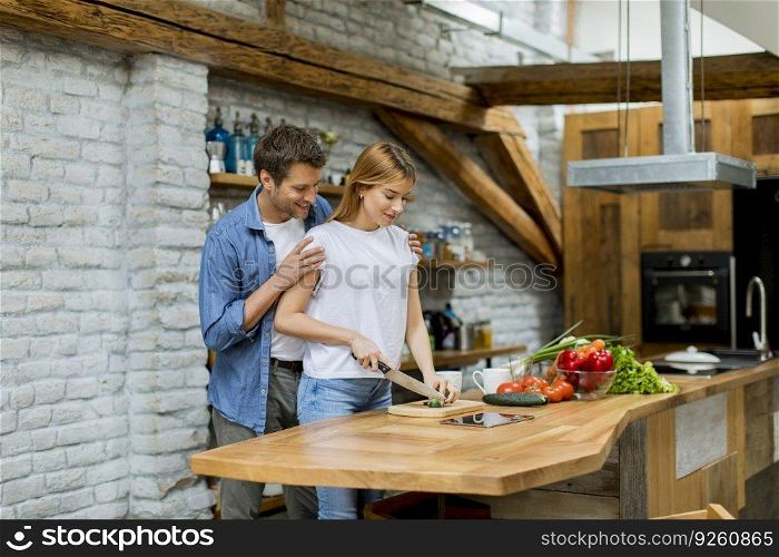 Lovely cheerful young couple cooking dinner together and having fun at rustic kitchen