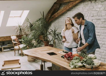 Lovely cheerful young couple cooking dinner together and having fun at rustic kitchen