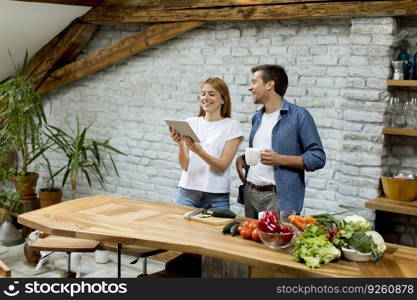 Lovely cheerful young couple cooking dinner together and having fun at rustic kitchen