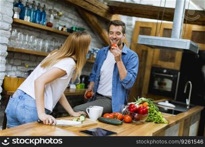 Lovely cheerful young couple cooking dinner together and having fun at rustic kitchen
