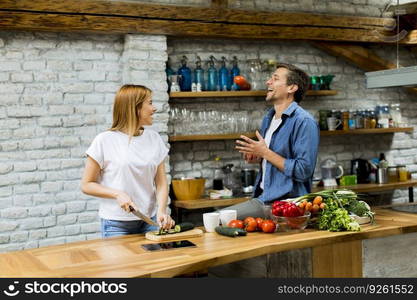 Lovely cheerful young couple cooking dinner together and having fun at rustic kitchen