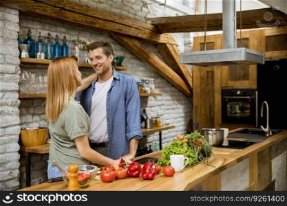 Lovely cheerful young couple cooking dinner together and having fun at rustic loft kitchen
