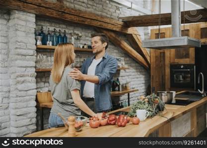 Lovely cheerful young couple cooking dinner together and having fun at rustic loft kitchen