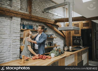 Lovely cheerful young couple cooking dinner together and having fun at rustic loft kitchen