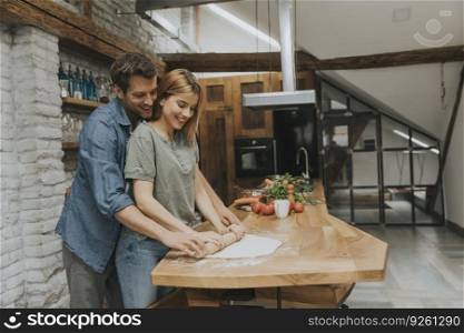 Lovely cheerful young couple cooking dinner together and having fun at the rustic kitchen
