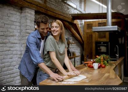 Lovely cheerful young couple preparing dinner together and having fun at the rustic kitchen