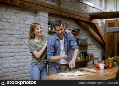 Lovely cheerful young couple preparing dinner together and having fun at the rustic kitchen
