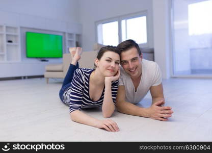 Lovely couple enjoying free time lying on the floor in their living room at home