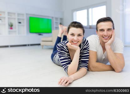 Lovely couple enjoying free time lying on the floor in their living room at home