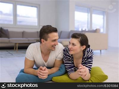 Lovely couple enjoying free time lying on the floor in their living room at home