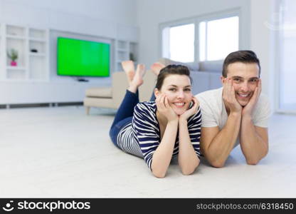 Lovely couple enjoying free time lying on the floor in their living room at home