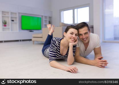 Lovely couple enjoying free time lying on the floor in their living room at home