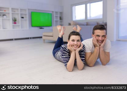 Lovely couple enjoying free time lying on the floor in their living room at home
