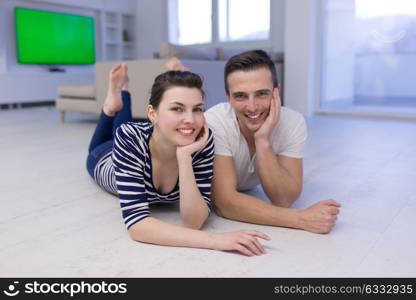 Lovely couple enjoying free time lying on the floor in their living room at home