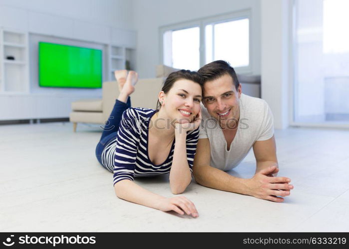 Lovely couple enjoying free time lying on the floor in their living room at home