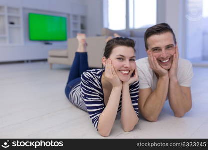 Lovely couple enjoying free time lying on the floor in their living room at home