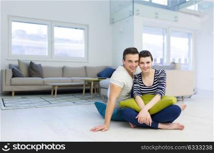 Lovely couple enjoying free time sitting on the floor in their living room at home