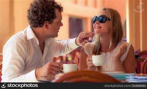 Lovely couple in a cafe having tea. Man cleaning womans face while she making funny grimace