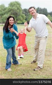 Lovely couples playing with their happy daughter at the park over natural background