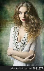 lovely dame with antique style and golden jewellery posing with curly long hair and looking in camera