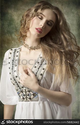 lovely dame with antique style and golden jewellery posing with curly long hair and relaxed expression