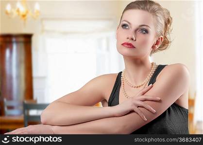lovely fashion shot of blond cute woman elegant dress and pearl necklace