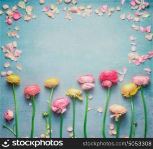 Lovely floral frame with colorful buttercups flowers and petals on turquoise rustic background. Festive greeting concept, flat lay, top view