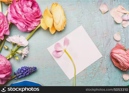 Lovely flowers composing with blank paper greeting card on shabby chic background, top view. Festive greeting card .