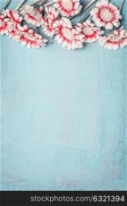 Lovely flowers on light blue background, floral border, top view, vertical. Creative layout for holidays greeting of Mothers day, birthday, wedding or happy event