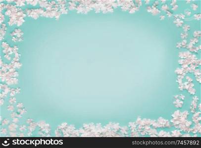 Lovely frame of little white flowers on turquoise blue background, top view, copy space. Flat lay
