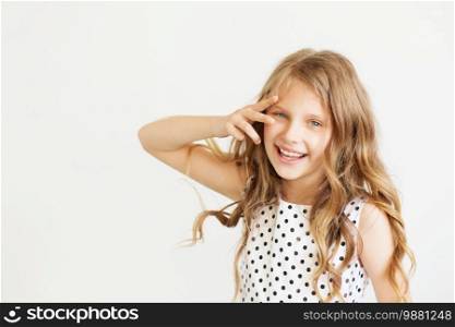 Lovely frisky little girl in a polka-dot dress against a white background. Happy kids