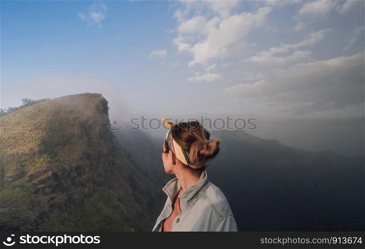 Lovely girl Standing at the back See high peaks, steep brilliant sky spectacular views and fog sprays. subject is blurred