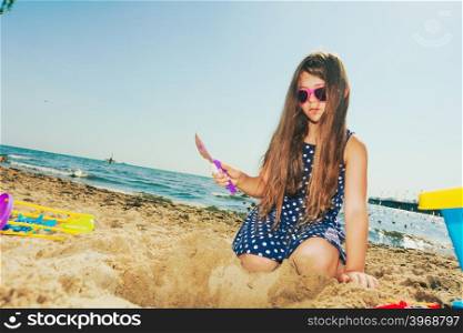 Lovely gorgeous little girl playing with sand.. Having fun and joy concept. Little lovely gorgeous long haired girl playing with sea sand. Playful active kid on beach in summer vacation.
