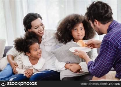 Lovely home happy family living together in living room father mother playing with daughter mix race.