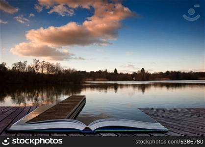 Lovely image of late sunset sky over calm lake landscape with long fishing jetty pier and vibrant colors coming out of pages in magical book
