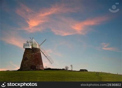 Lovely image of old windmill at sunset on top of hill with vibrant sky