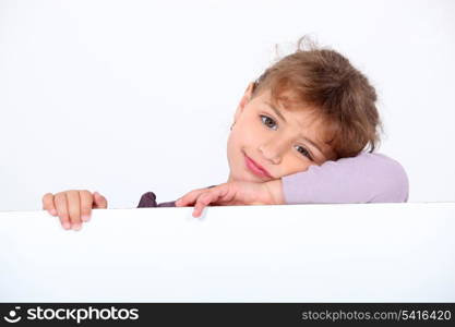 Lovely little girl leaning on a white panel